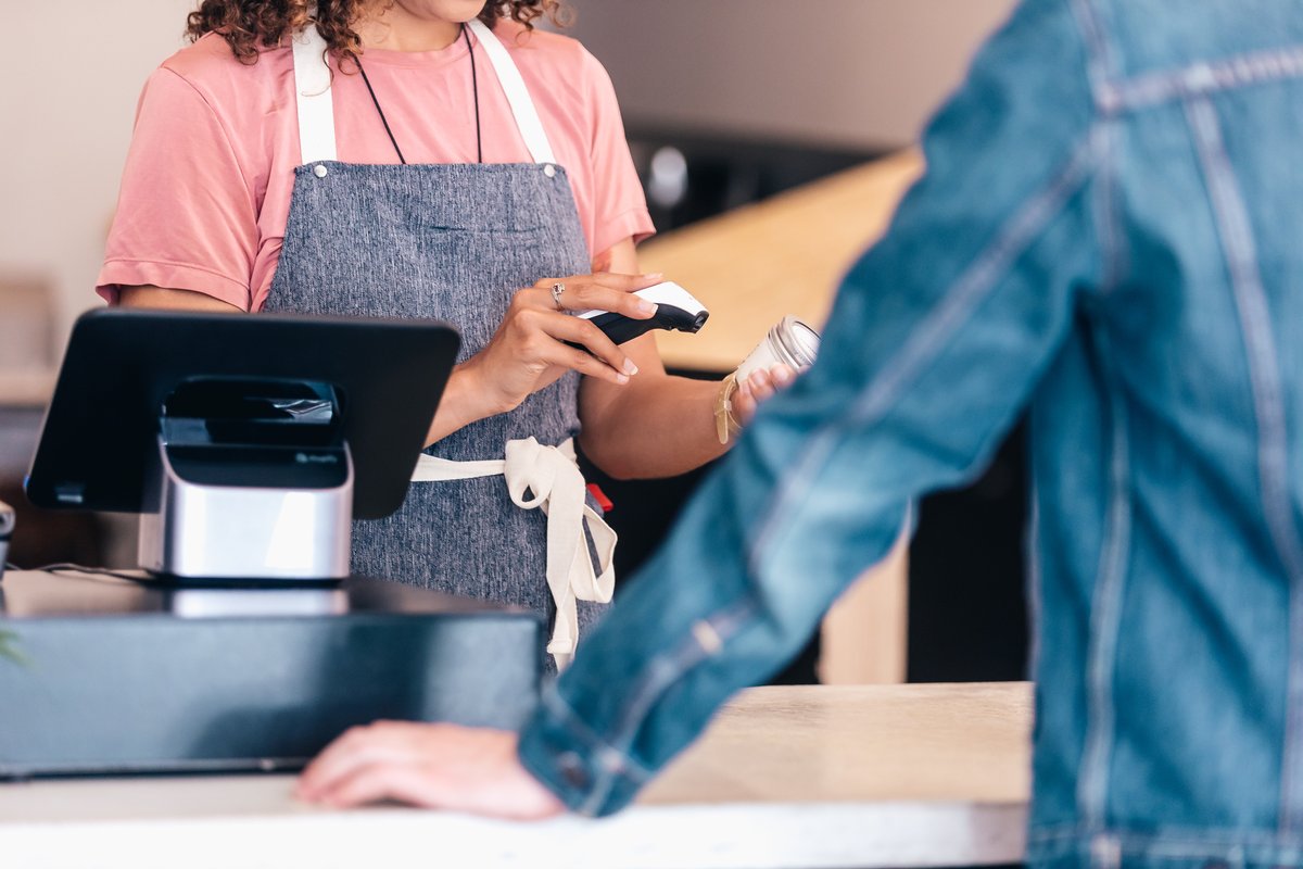 Retail cashier using Vendra point-of-sale system to scan products at checkout
