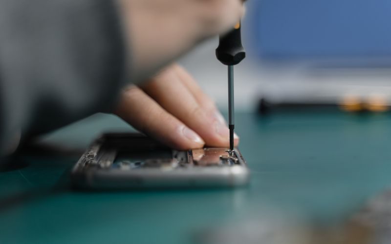 Vendra electronics repair shop software — technician repairing devices